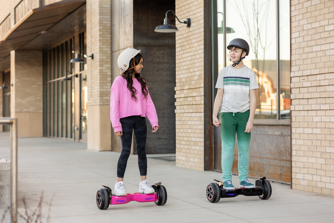 Two children riding GOTRAX Pink and Black E4 Off-Road Hoverboard